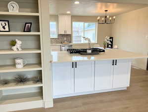 Kitchen with white cabinets, light wood finished floors, light stone countertops, tasteful backsplash, and recessed lighting