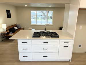 Kitchen with white cabinets, light stone counters, light wood-type flooring, stainless steel gas cooktop, and recessed lighting