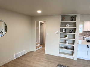 Unfurnished dining area featuring built in features, light wood finished floors, stairway, and recessed lighting