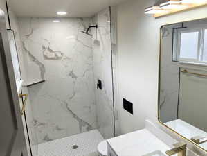 Bathroom with vanity and a marble finish shower