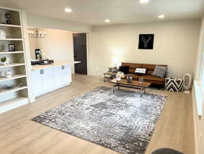 Living area with light wood-style flooring, recessed lighting, and a chandelier
