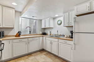 Kitchen with appliances with stainless steel finishes, light countertops, a textured ceiling, white cabinetry, and recessed lighting