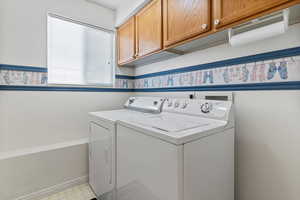 Washroom featuring cabinet space, washing machine and clothes dryer, and light floors