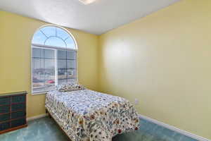 Bedroom featuring dark colored carpet and a textured ceiling