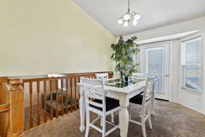 Dining room featuring carpet floors, lofted ceiling, and a chandelier