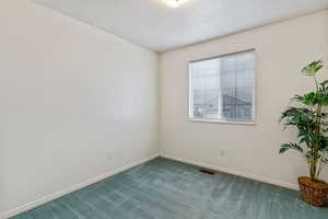 Carpeted empty room featuring baseboards and a textured ceiling