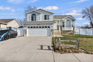 Split level home featuring a garage, concrete driveway, and a gate