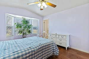 Bedroom with lofted ceiling, ceiling fan, and dark wood finished floors