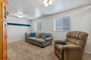 Living area with light colored carpet and a textured ceiling