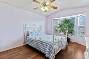 Bedroom with vaulted ceiling, dark wood finished floors, and ceiling fan
