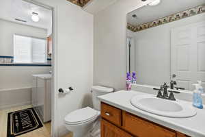 Bathroom with vanity, a textured ceiling, washing machine and dryer, a garden tub, and light flooring
