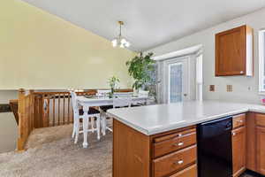 Kitchen featuring brown cabinets, light countertops, lofted ceiling, a peninsula, and pendant lighting