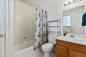 Full bath with shower / tub combo with curtain, vanity, and light flooring