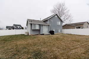 Rear view of house with a fenced backyard and a shingled roof
