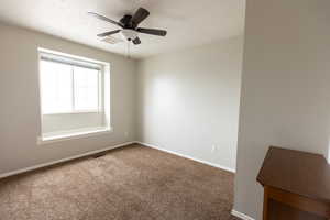 Carpeted empty room with baseboards and a ceiling fan