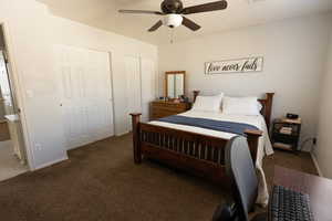 Bedroom with multiple closets, dark carpet, and a ceiling fan