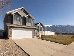View of front of home with a mountain view, a garage, driveway, and brick siding