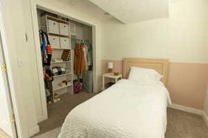 Bedroom featuring carpet flooring, a closet, and a textured ceiling