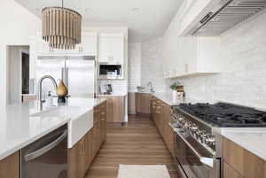 Kitchen featuring high end appliances, light stone counters, extractor fan, modern cabinets, and recessed lighting