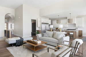 Living area featuring arched walkways, light wood-style flooring, and a towering ceiling