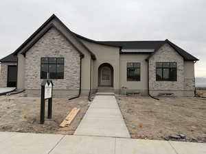 View of front of home with stone siding, stucco siding, and a metal roof