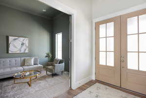 Entryway featuring french doors, crown molding, and wood finished floors