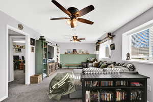 Carpeted living room with a desk and a ceiling fan