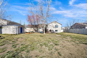Back of house with a fenced backyard and an outbuilding
