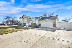 Tri-level home with brick siding, driveway, a gate, a garage, and a shingled roof