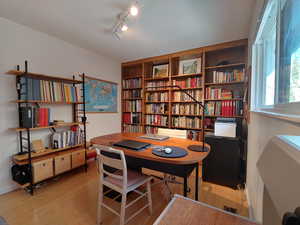 Bedroom with large window and full wall wooden bookcase.