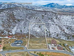 Snowy aerial view with a mountain view and property boundaries highlighted