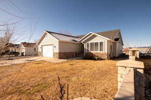 View of front of home featuring stone siding, concrete driveway, a shingled roof, and an attached garage
