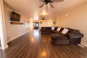 Living area with dark wood-style flooring, a ceiling fan, and a textured ceiling