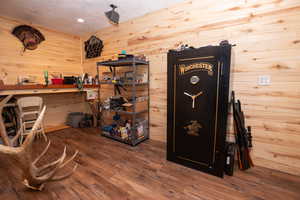 Office featuring dark wood-type flooring, wood walls, a workshop area, and recessed lighting