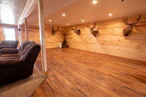 Living room featuring hardwood / wood-style floors, wooden walls, and recessed lighting