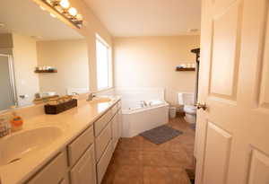 Bathroom featuring a garden tub, double vanity, a shower stall, and light tile patterned floors