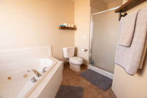 Full bath featuring a stall shower, light tile patterned floors, and a jetted tub