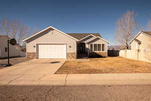Ranch-style house featuring stone siding, concrete driveway, and an attached garage