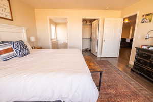 Bedroom with a spacious closet, dark wood-style floors, and connected bathroom