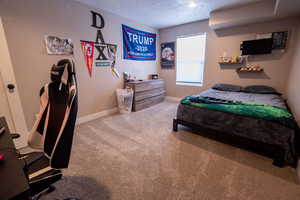 Carpeted bedroom featuring baseboards and a textured ceiling