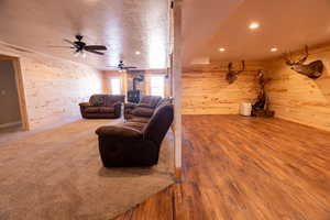 Living area featuring a wood stove, wood walls, light wood-style flooring, recessed lighting, and a textured ceiling