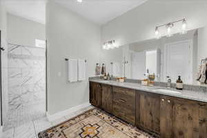 Full bathroom featuring double vanity and a tile shower