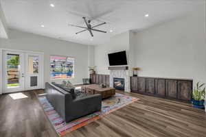 Living area featuring a fireplace, dark wood-style floors, a ceiling fan, and recessed lighting