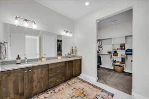 Full bath featuring a spacious closet, double vanity, recessed lighting, and light marble finish flooring