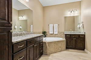 Bathroom featuring two vanities and a garden tub