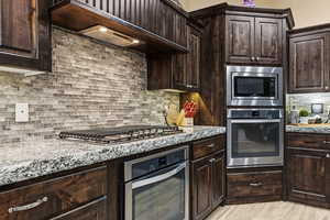 Kitchen featuring dark brown cabinets, premium range hood, and stainless steel appliances