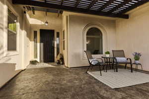 View of exterior entry with a patio area, a pergola, and stucco siding