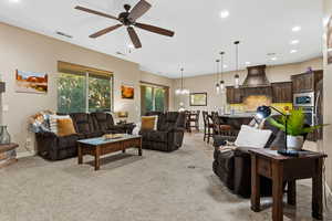 Living room featuring recessed lighting, light carpet, a chandelier, and ceiling fan