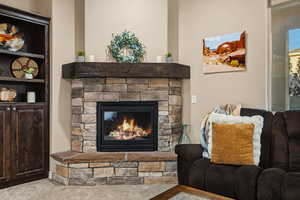 Carpeted living room with a stone fireplace