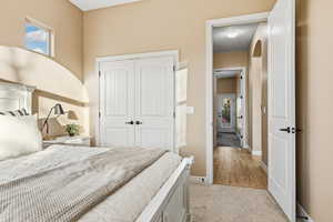 Bedroom with light colored carpet, a closet, and arched walkways